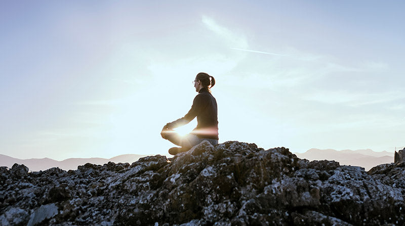 woman meditating on top of a mountain